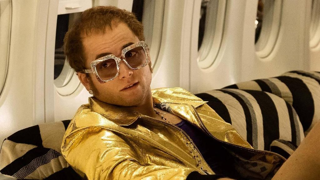 Elton John (Taron Egerton) is seated in a private flight in "Rocketman".